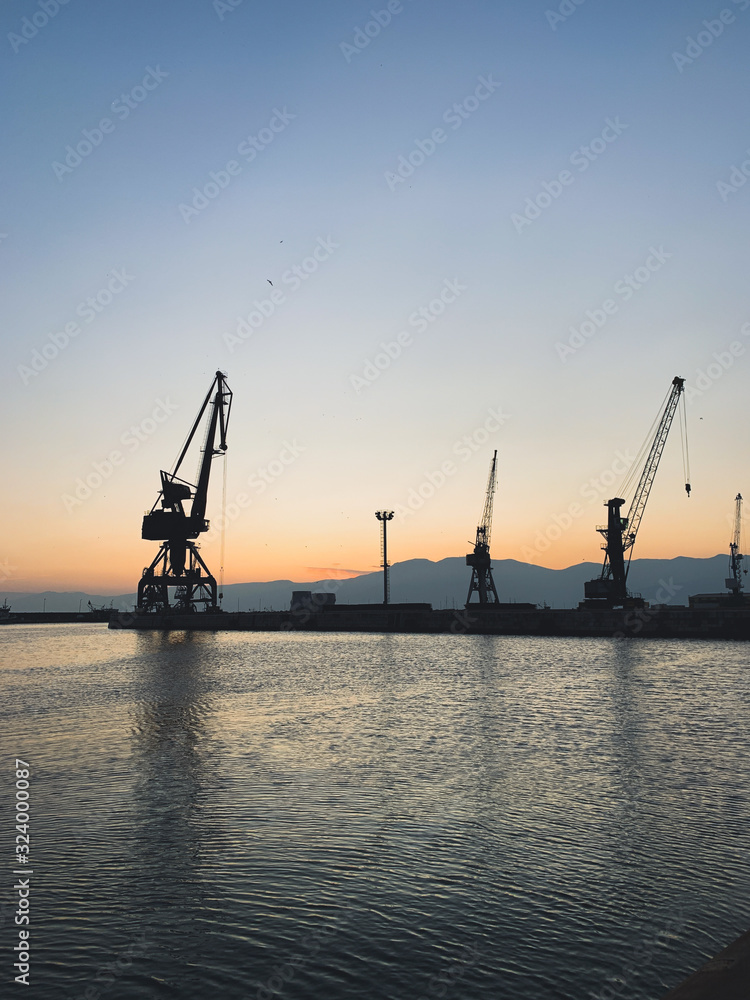 Silhouettes of the cranes in the sea port