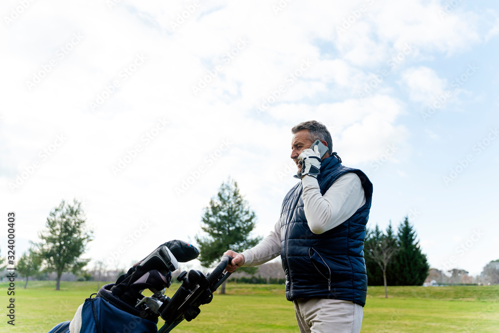 Senior using his smartphone while playing a game of golf Senior using his smartphone while playing a game of golf