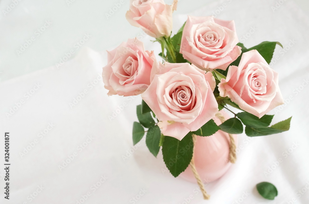 Beautiful pink roses in a pink vase on white table top view. Home interiour. Pastel colors