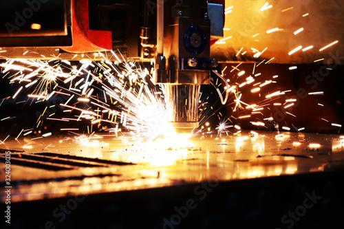 Industrial laser cuts a thick sheet of metal. Molten metal scatters in all directions