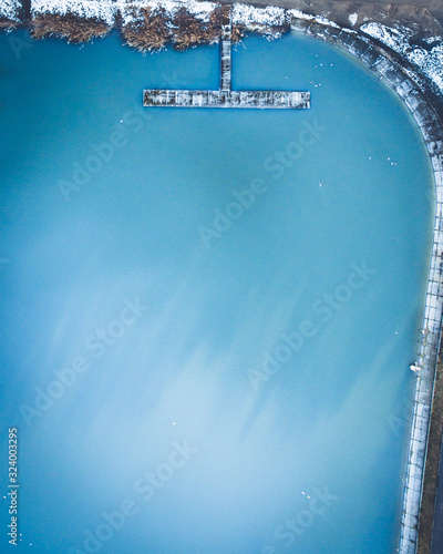 Aerial view of the winter lake with clear blue sea water and boat. Abstract pict