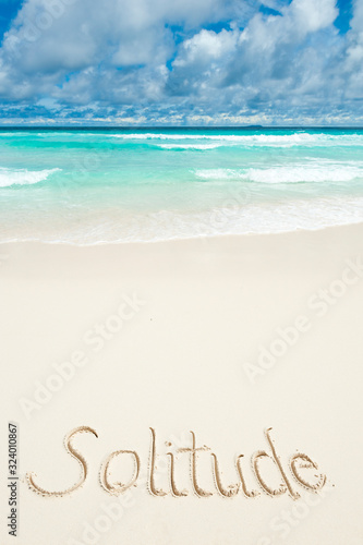 Solitude message written in smooth sand on bright tropical beach