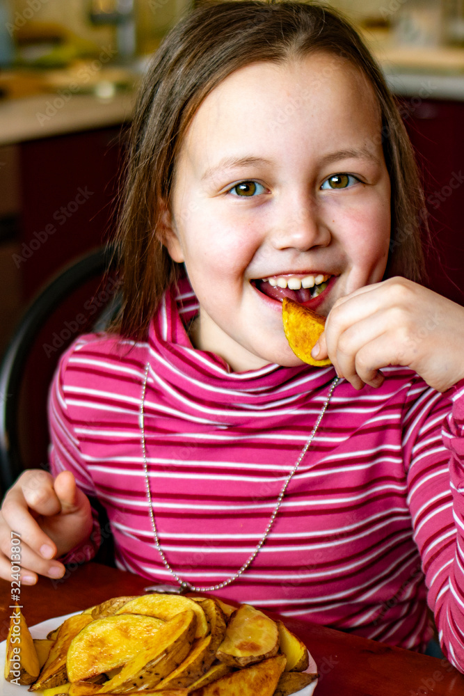 Girl eats vegetables. Portrait of happy child smiling eating fried potatoes.Girl eating healthy fried potatoes for lunch. Girl eats vegetables. Portrait of happy child smiling eating fried potatoes.Girl eating healthy fried potatoes for lunch.