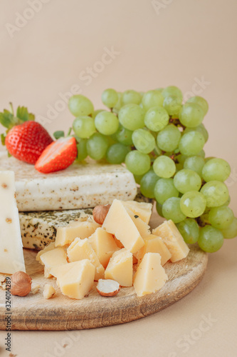 Two large pieces of salted pork lard and tasty cheese with hazelnut, strawberry and grape on old wooden board background. Rustic style. A delicious snack with bacon