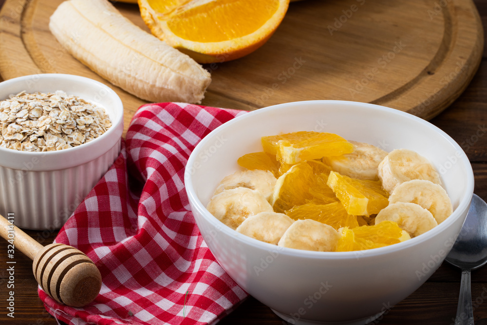 Bowl of oatmeal porridge with banana and orange on wooden background, copy space Bowl of oatmeal porridge with banana and orange on wooden background, copy space