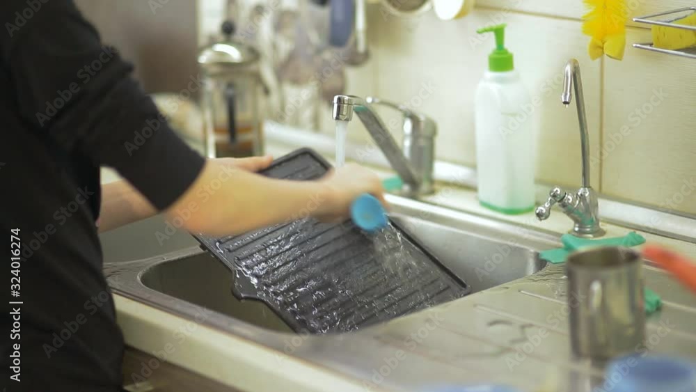 washing dirty dishes under the kitchen tap. Housekeeper's routine washing dirty dishes under the kitchen tap. Housekeeper's routine