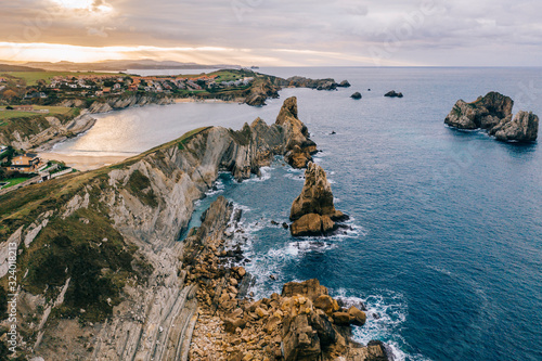 Amazing aerial landscape of steep rocky shore and breathtaking wavy ocean in cloudy day in Pielagos, Cantabria, Santander, Spain