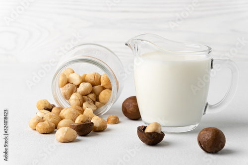 Dairy-free milk. Macadamia nut milk in a small glass jug on a light surface. Dairy products without lactose. Horizontal orientation, close-up.