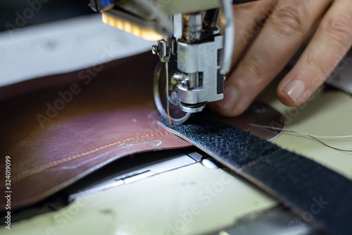 Shoemaker sewing a leather and velcro for making a shoe. Shoe sewing machine needle in focus. Sewing leather in focus. Shoe industry. 