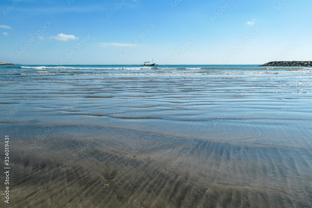 Sandy shore of Seminyak Beach on Bali, Indonesia. The shallow sea water leaves nice traits on the sand. Nature is a painter. There is an island in the back. Calm surface of the sea. Idyllic beach Sandy shore of Seminyak Beach on Bali, Indonesia. The shallow sea water leaves nice traits on the sand. Nature is a painter. There is an island in the back. Calm surface of the sea. Idyllic beach