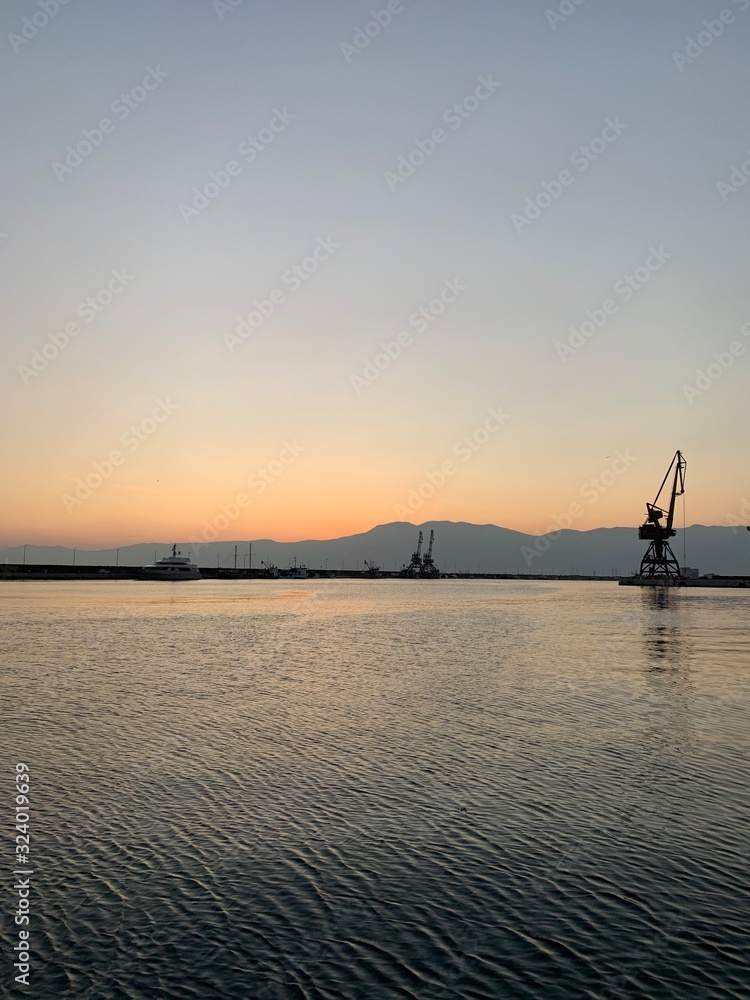 Silhouettes of the sea port cranes background at the sunset, natural colors