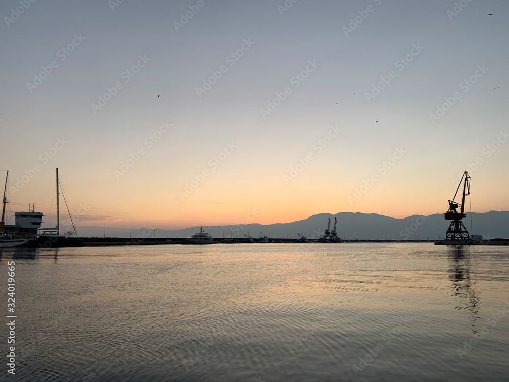 Silhouettes of the sea port cranes background at the sunset, natural colors Silhouettes of the sea port cranes background at the sunset, natural colors
