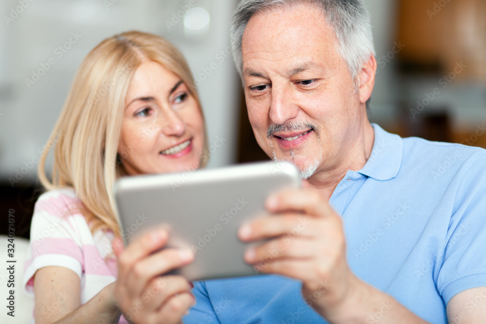 Portrait of a smiling mature couple using digital tablet on sofa at home Portrait of a smiling mature couple using digital tablet on sofa at home