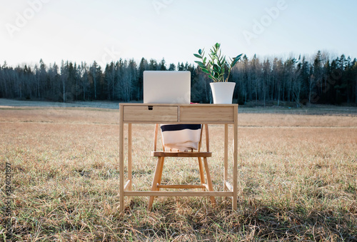 A desk and laptop home office in the middle of a field outdoors photo