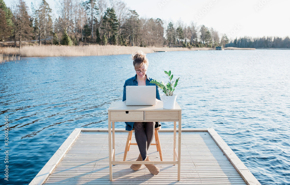 woman flexible working on a desk on a pier at the beach woman flexible working on a desk on a pier at the beach