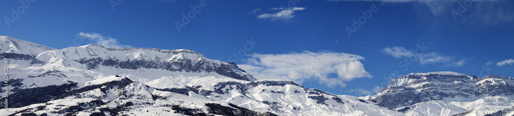 Large panorama of high snowy mountains and blue sky with clouds