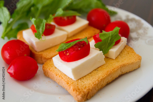 Beautiful breakfast: toasts with goat cheese, tomatoes and Basil on a white plate
