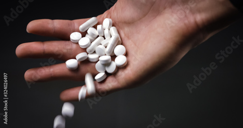 Holding medical pills and tablets and dropping them on black background