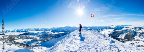 winter sports: snow shoe hiker a the summit of the snowy mountain in the swiss alps. panoramic switzerland mountain range