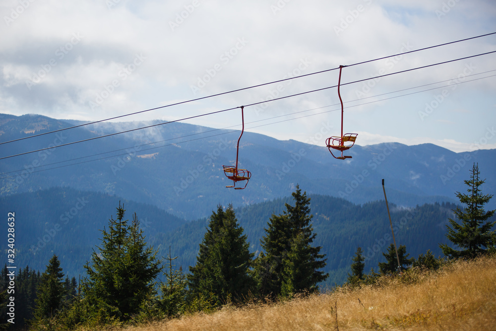 Cable car in the ski area of Bulgaria in summer. Yellow chair ski lift is among the green firs and pines in the Rhodope mountains