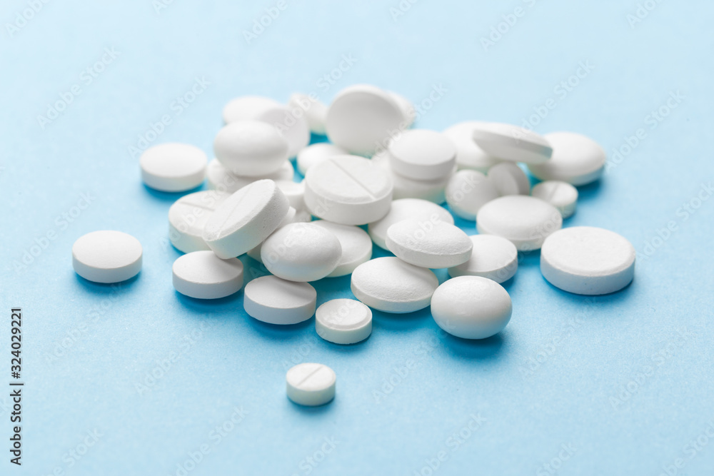 scattered white pills on a blue table. Layout for special offers such as advertising or other ideas. The concept of medicine, pharmacy and healthcare. Space for copy. flat lay for text or logo. scattered white pills on a blue table. Layout for special offers such as advertising or other ideas. The concept of medicine, pharmacy and healthcare. Space for copy. flat lay for text or logo.
