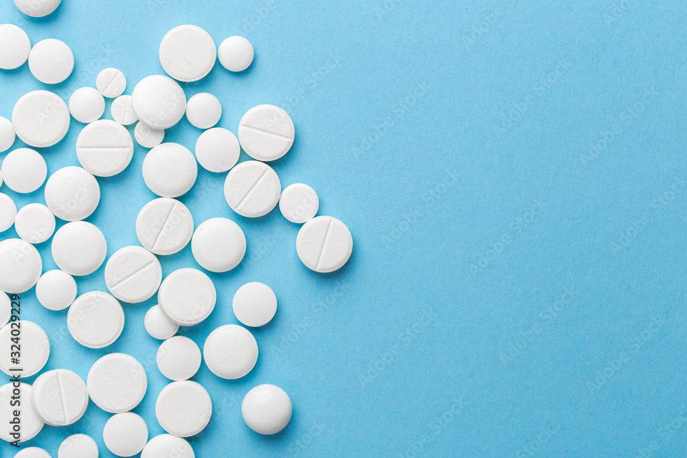 scattered white pills on a blue table. Layout for special offers such as advertising or other ideas. The concept of medicine, pharmacy and healthcare. Space for copy. flat lay for text or logo.