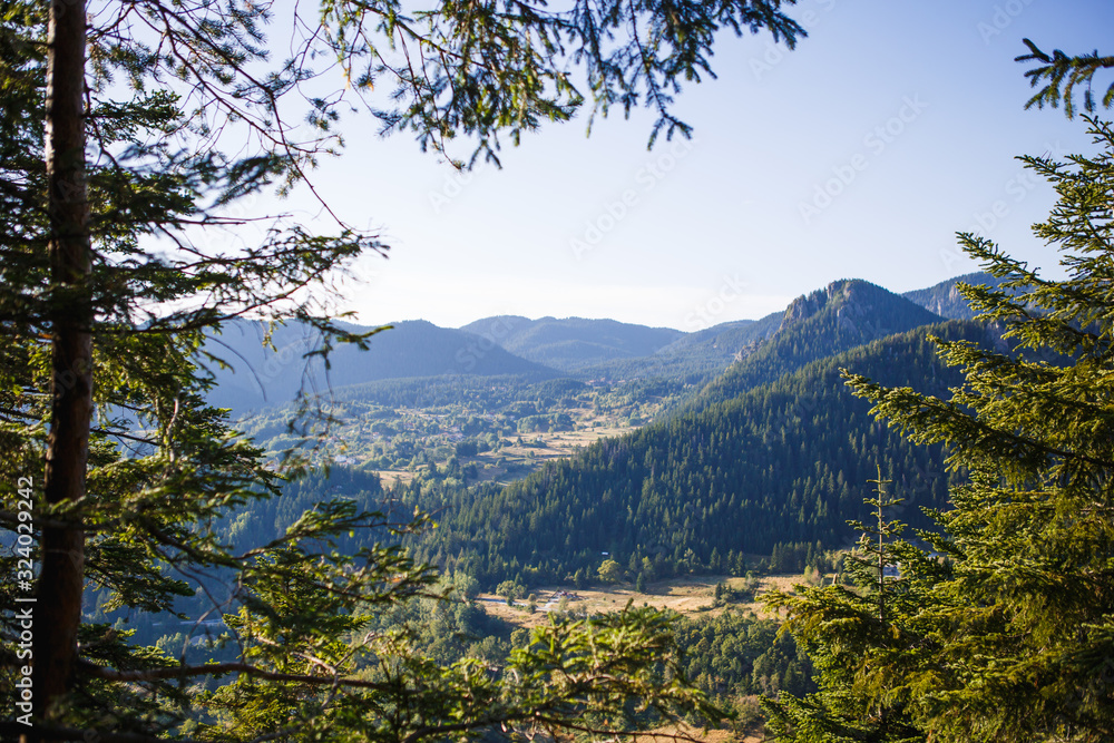 Panoramic top view of the green mountain valley from the top of the cliff in autumn in the Balkans. Mountain village in the Rhodope mountains in Bulgaria Panoramic top view of the green mountain valley from the top of the cliff in autumn in the Balkans. Mountain village in the Rhodope mountains in Bulgaria