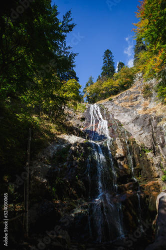 Streams of the waterfall fall from the rock and sparkle in the sun among the greenery. Attractions of Bulgaria - Krushuna waterfalls and mountain trail in Smolyan