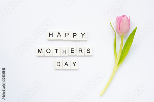 Text Happy Mother's Day made of wooden cubes with tulip flower isolated on white. Flat lay
