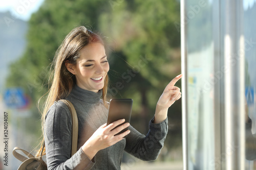 Commuter checks phone and schedule table in a bus stop