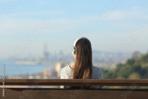 Woman wearing headphones listening to music on a bench