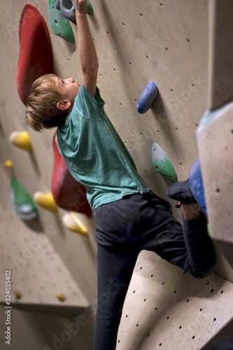  Boy climbing bouldering in boulder hall 