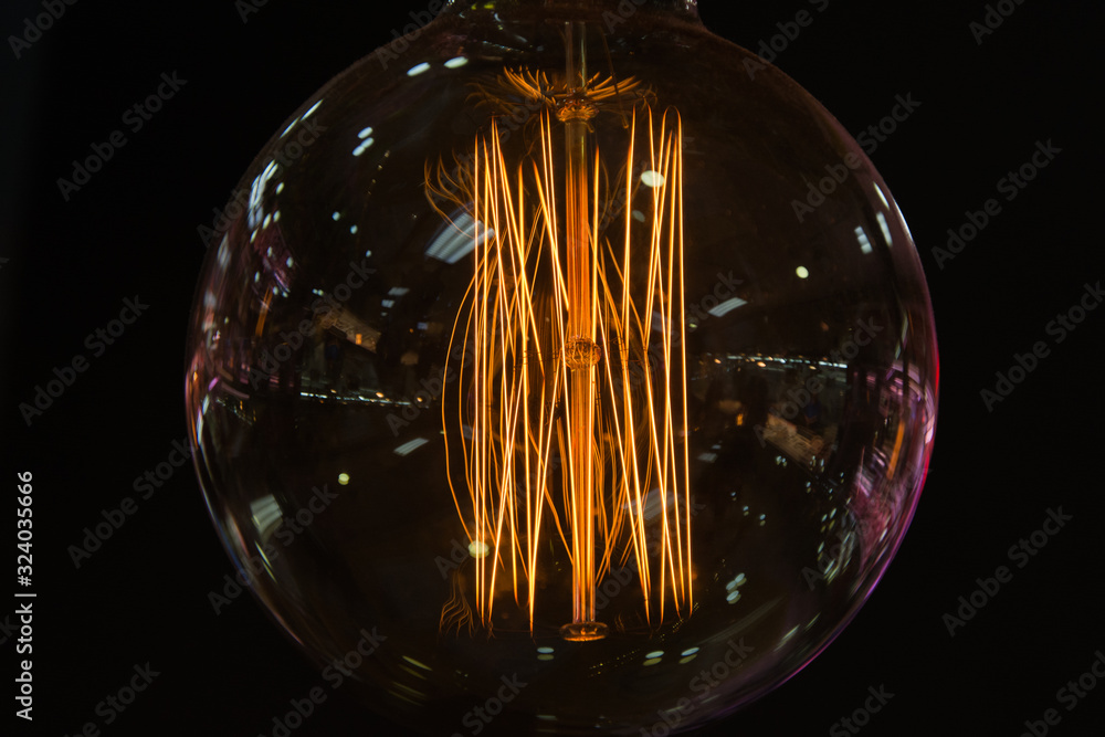 round lit bulb with filaments, dark background