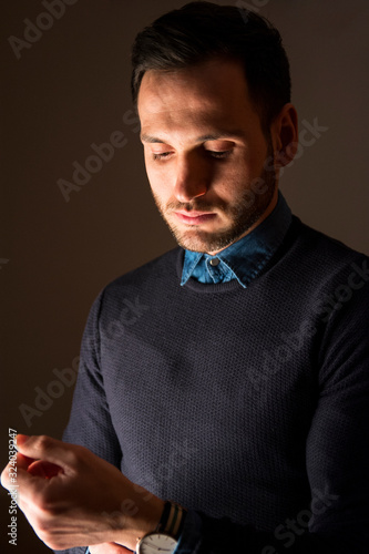 Portrait of a handsome man tying shirts. Stylish attitude. Businessman with watch.