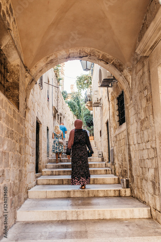 Portrait of beautiful woman with hijab sitting on street stairs in old city of Dubrovnik, Croatia. She is happy and relaxed.