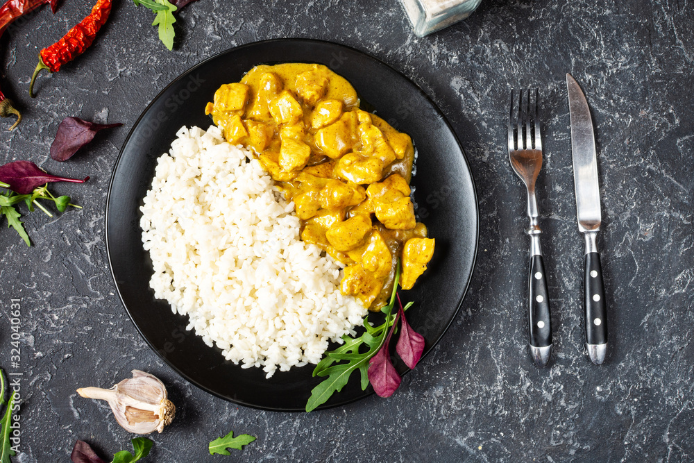Rice with chicken in curry sauce on a plate with horizontal top view. - obrazy, fototapety, plakaty 