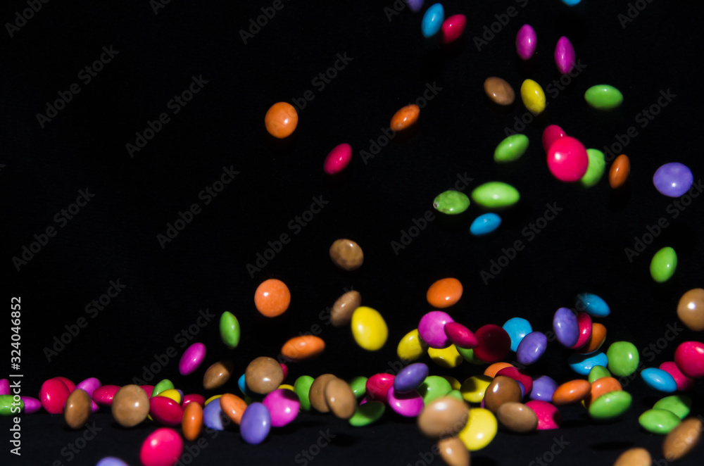 Many sweet and colourful candies are falling down to the table