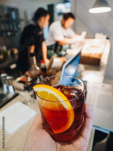 Red alcohol cocktail in glass with orange and ice
