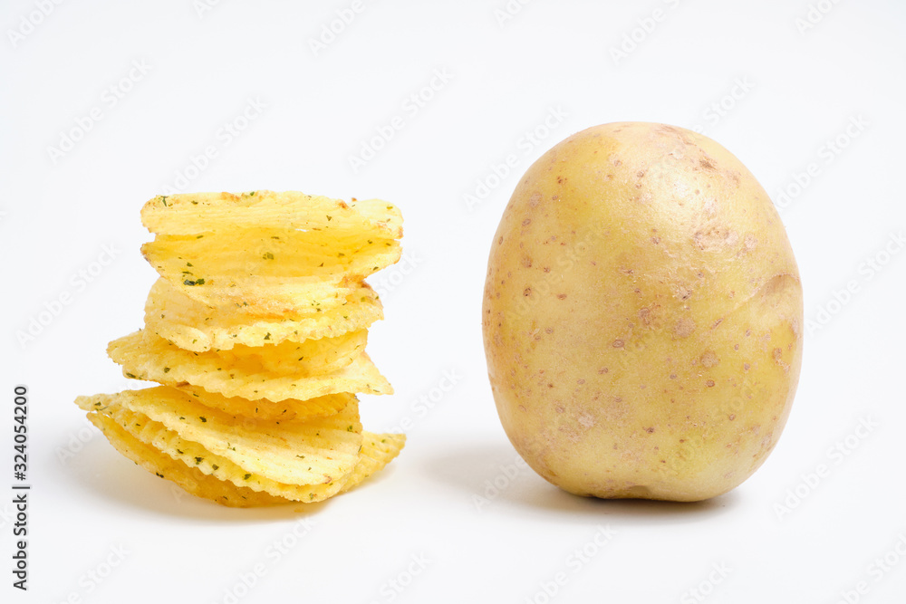 A stack of chips with spices next to a clean potato on a white background.