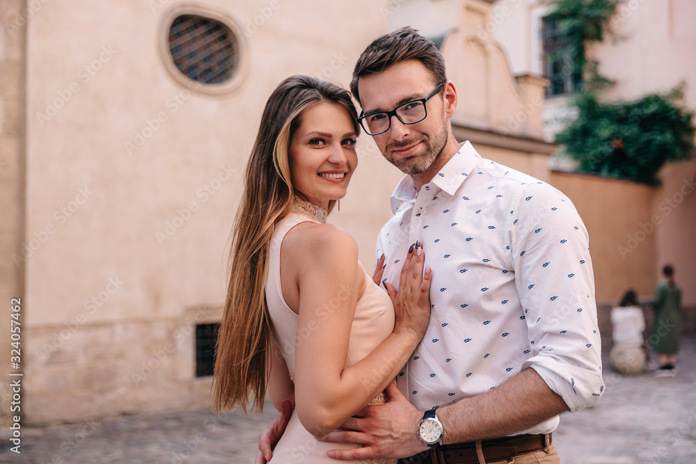 guy and girl in each other's arms look at camera and smile. city guy and girl in each other's arms look at camera and smile. city