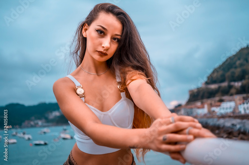 Lifestyle, a young sexy brunette with a white top clutched in a white railing