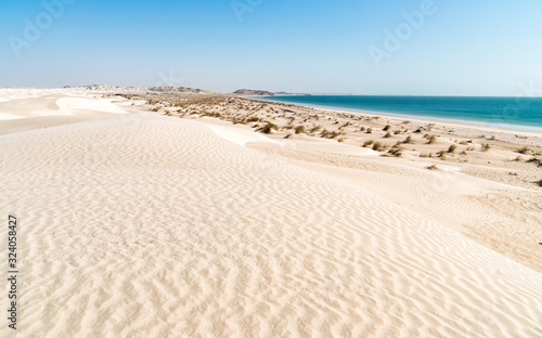 Landscape of Al Khaluf beach with dunes and white sands in the Arabian Sea of Oman.