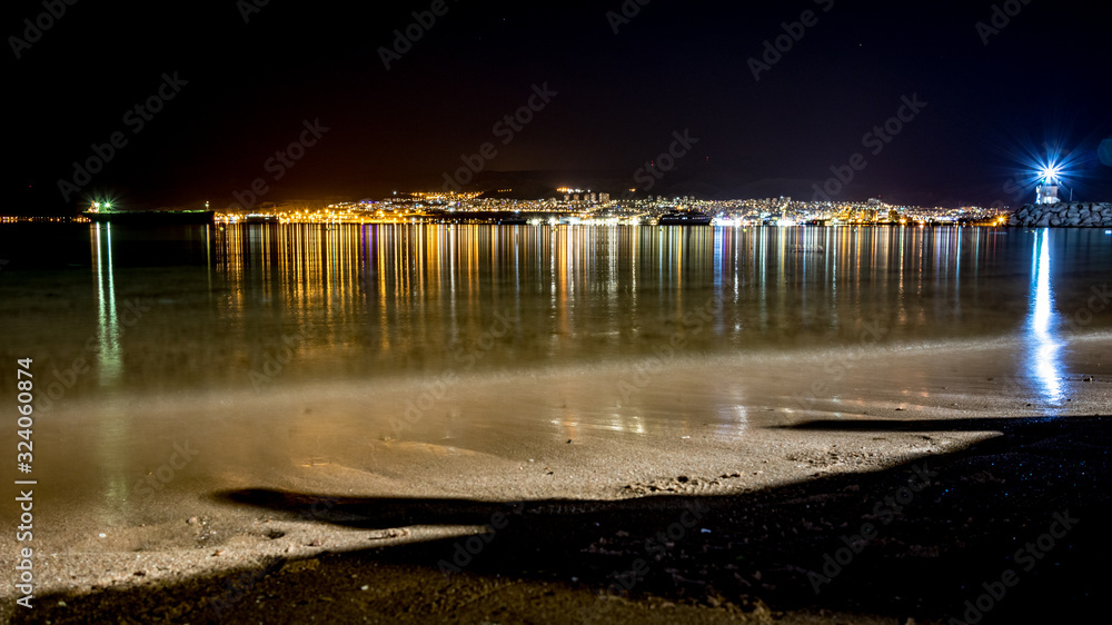Jordan, Israel and Egypt. Long exposure at coast of Gulf of Aqaba on Red Sea, winter night. Travel to Middle East, kingdom of Jordan. Three countries presented in single photograph, water reflections