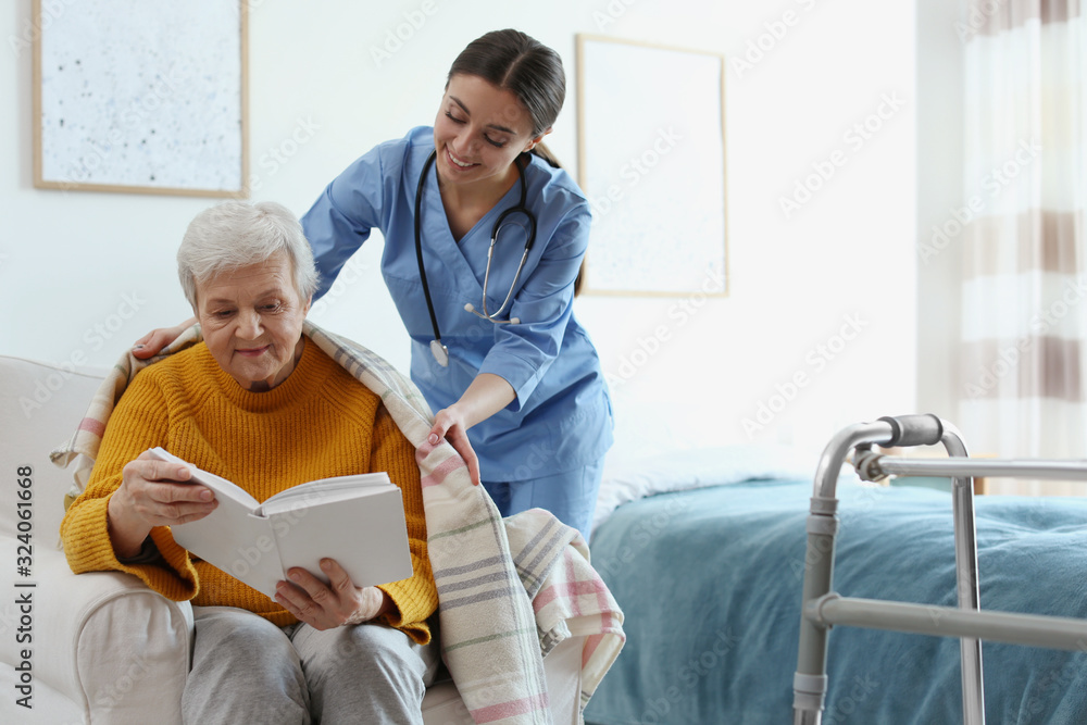Care worker covering elderly woman with plaid in geriatric hospice Care worker covering elderly woman with plaid in geriatric hospice