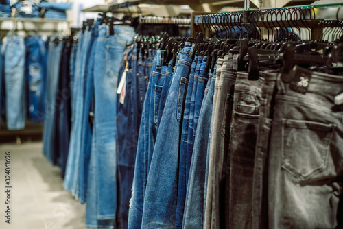 Row of hanged blue jeans. Jeans store in a shopping center. Denim sales. Blue pants. Shopping for women. Moll. © irishasel
