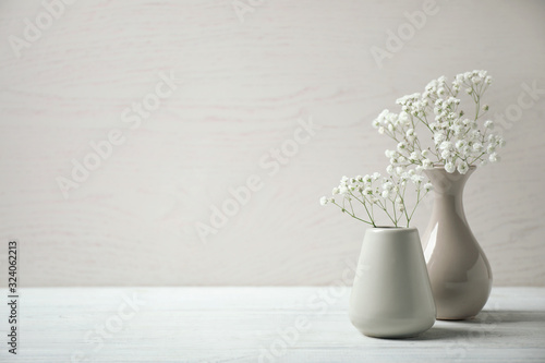 Картината върху платно Gypsophila flowers in vases on table against light background