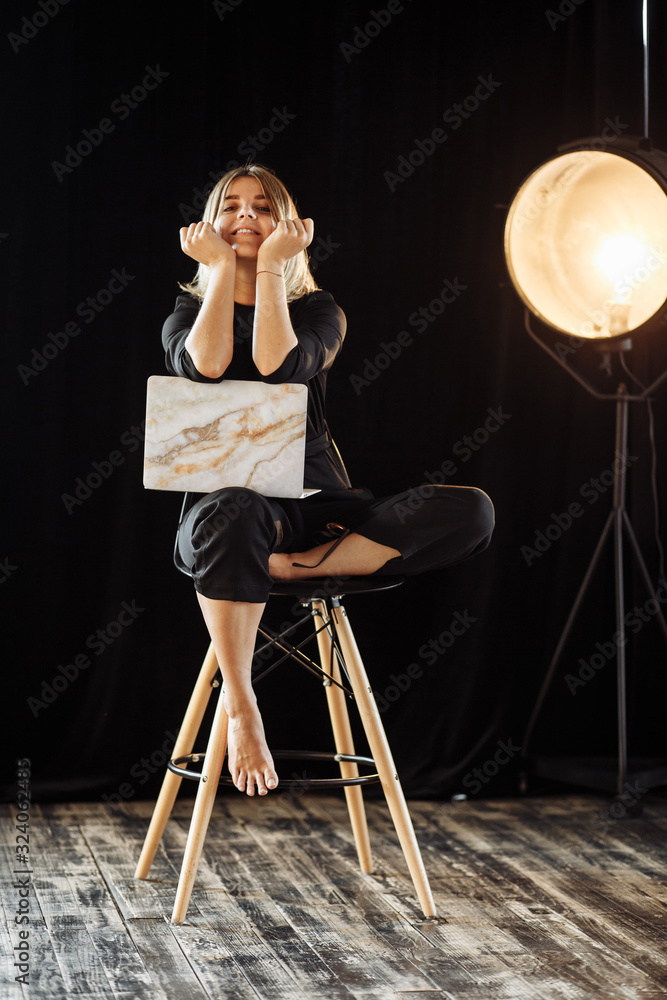 beautiful girl in a black suit sits on a chair and a desk with a laptop beautiful girl in a black suit sits on a chair and a desk with a laptop