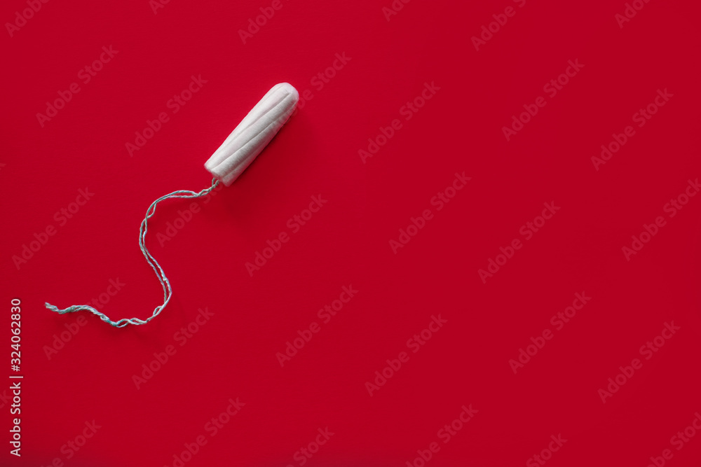 Medical female swab on a red background, top view, female menstruation, blood absorbent, critical days, female accessory Medical female swab on a red background, top view, female menstruation, blood absorbent, critical days, female accessory
