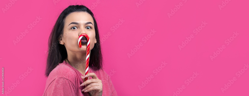 Portrait of lovely sweet beautiful cheerful woman with straight brown hair trying to bite red candy cane christmas. Portrait of lovely sweet beautiful cheerful woman with straight brown hair trying to bite red candy cane christmas.
