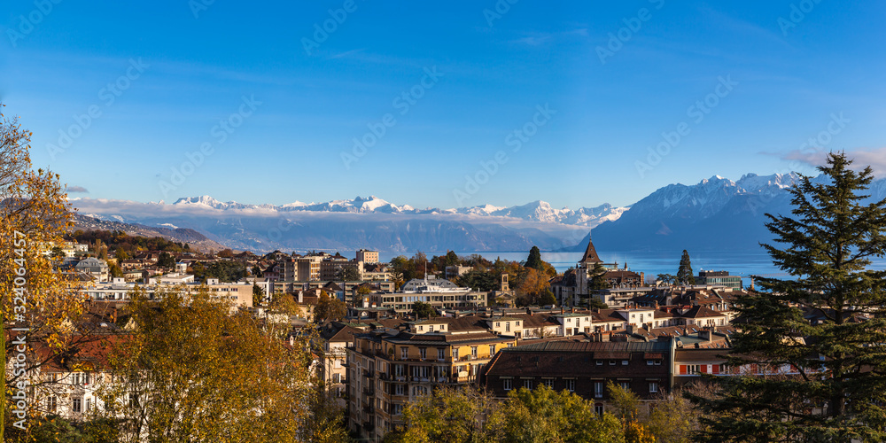 Aerial panorama view of Lausanne cityscape with snow covered French Alps and Lake Geneva (Lake Leman) in background on a sunny autumn day with blue sky cloud, Canton of Vaud, Switzerland